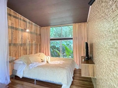 Habitación moderna con cama doble y ventana con vista verde en apartamento Salento Stay