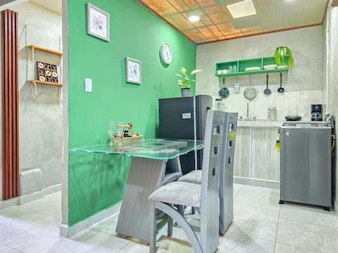 Cocina moderna con comedor integrado en apartamento Salento Stay con pared verde y electrodomésticos completos