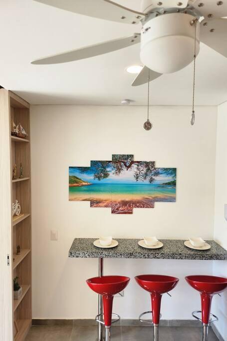 Comedor moderno con barra de granito y sillas rojas en apartamento premium Santa Marta
