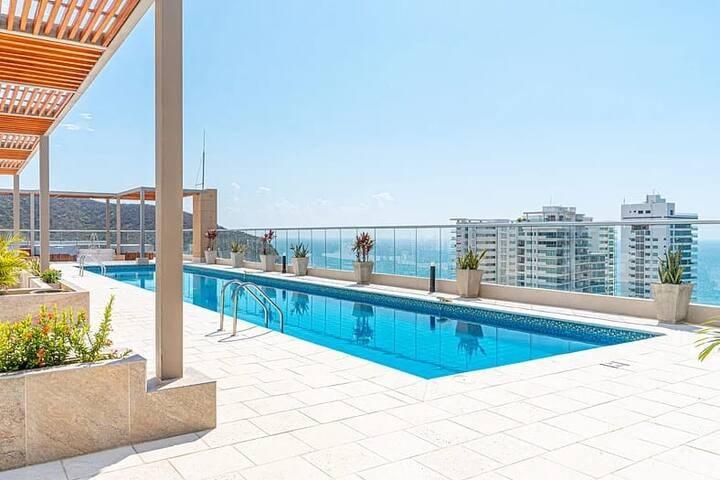 Piscina en terraza de Premium Suite con vista al mar y edificios modernos en Santa Marta
