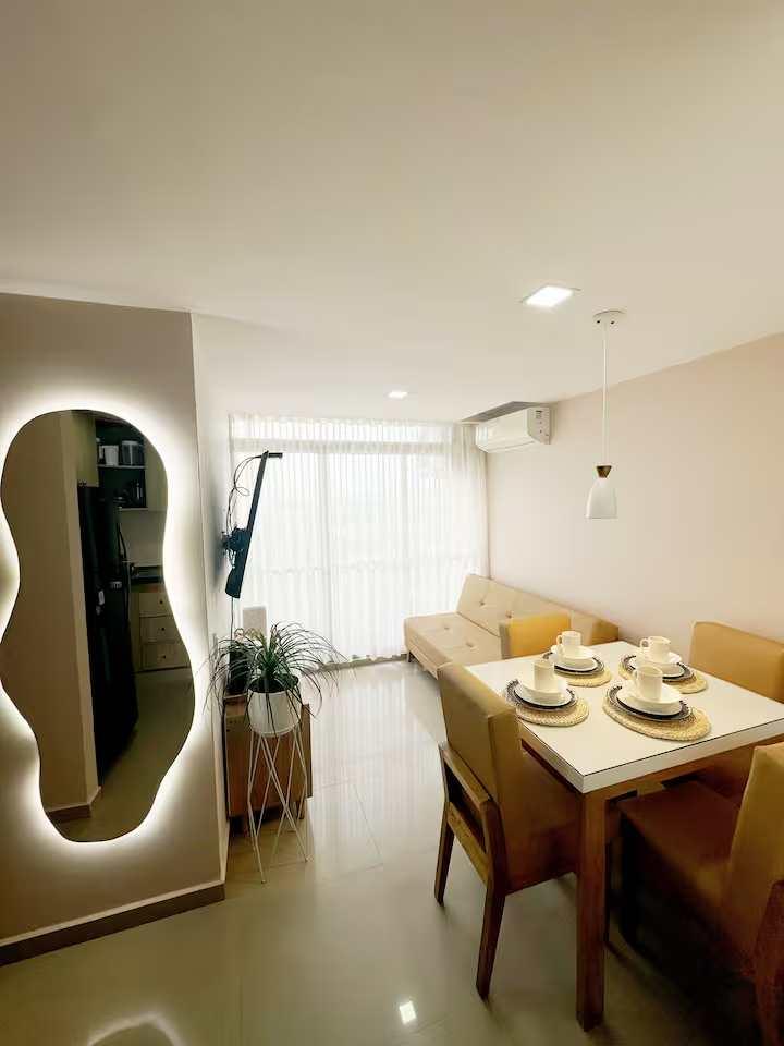 Comedor moderno con mesa de madera y espejo iluminado en apartamento de Cartagena de Indias