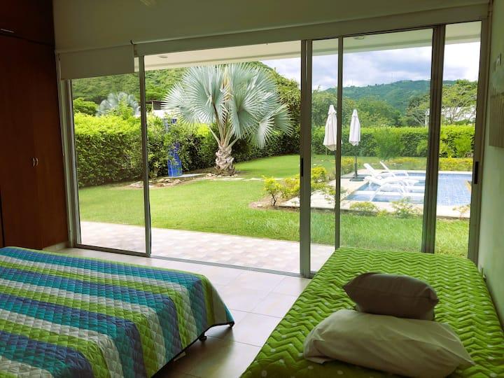 Habitación con vista al jardín tropical y piscina en casa de alquiler en Apulo