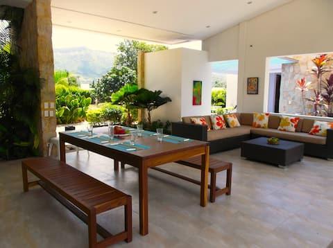 Sala comedor moderna con vista tropical en casa vacacional Apulo con muebles contemporáneos