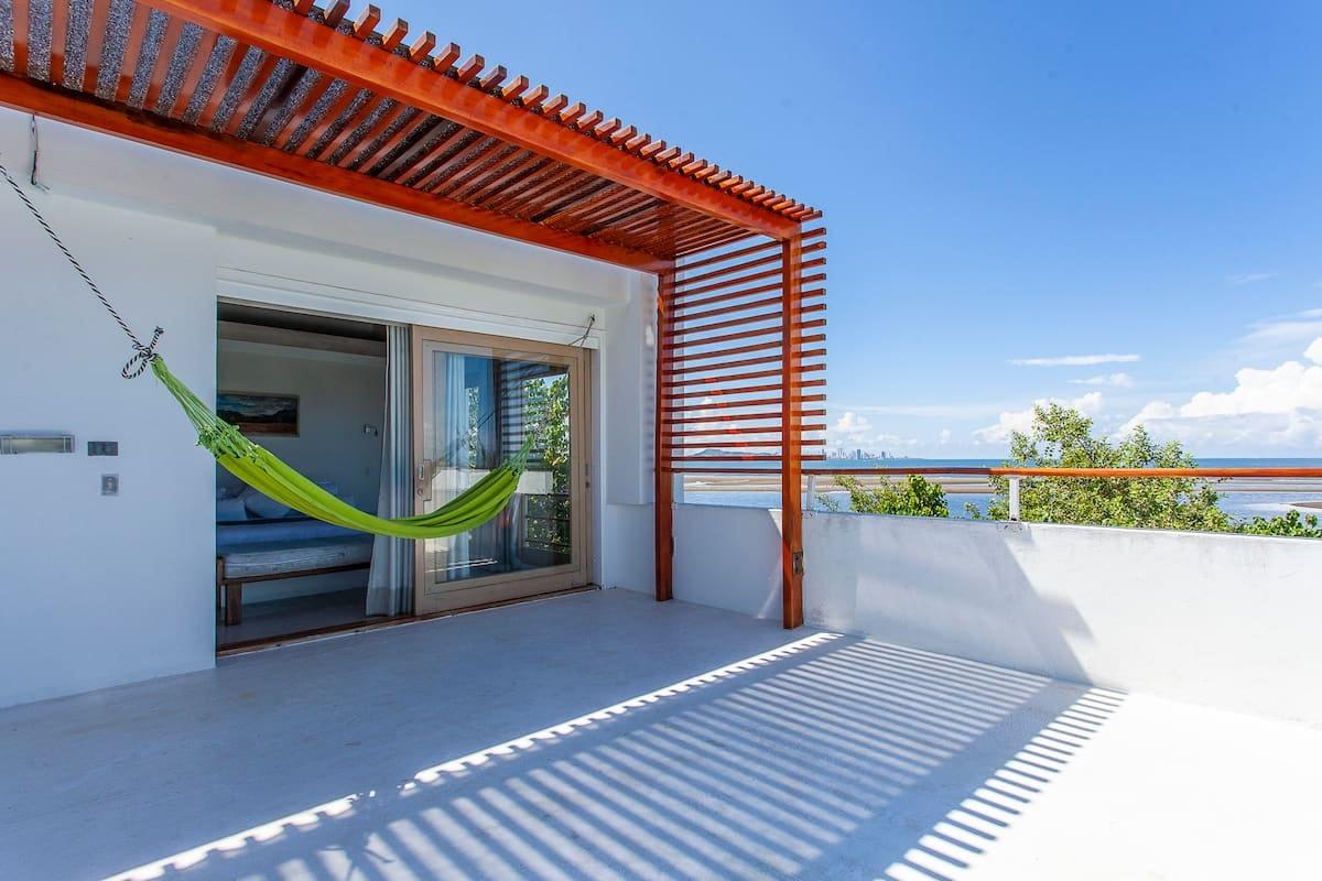 Terraza con hamaca verde y pergola de madera en villa frente al mar en Cartagena