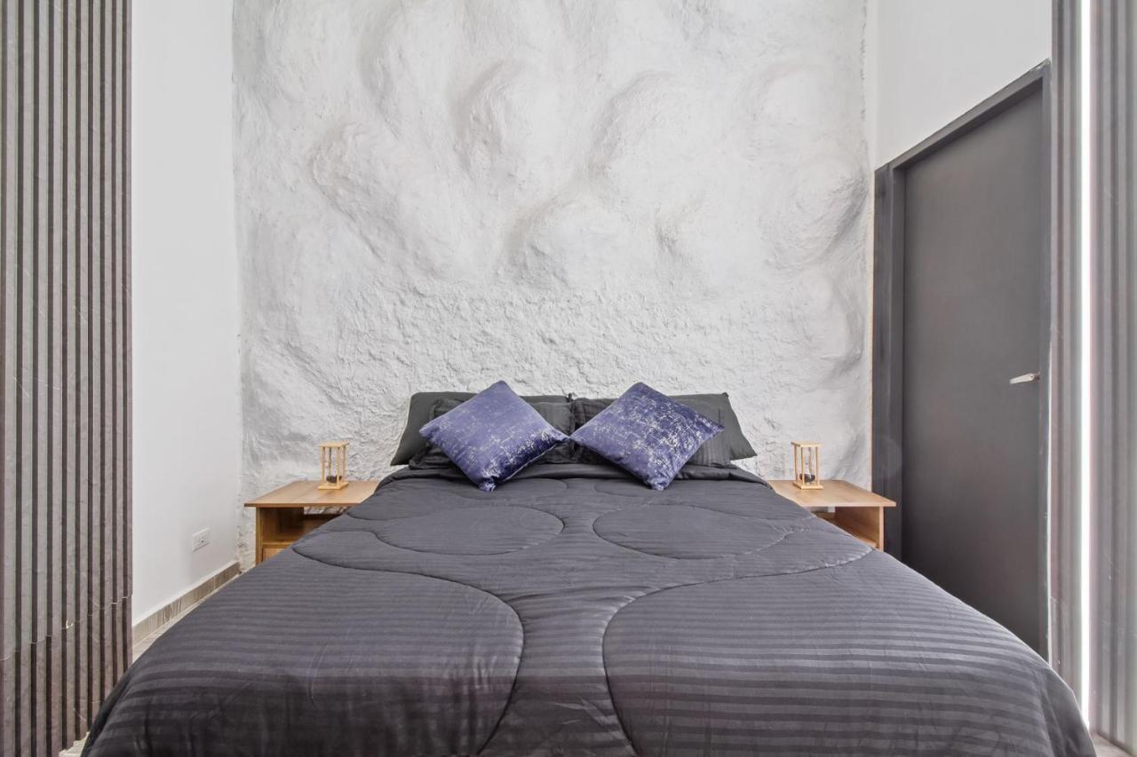 Habitación moderna con cama doble y pared texturizada en apartamento de 6 habitaciones en Medellín