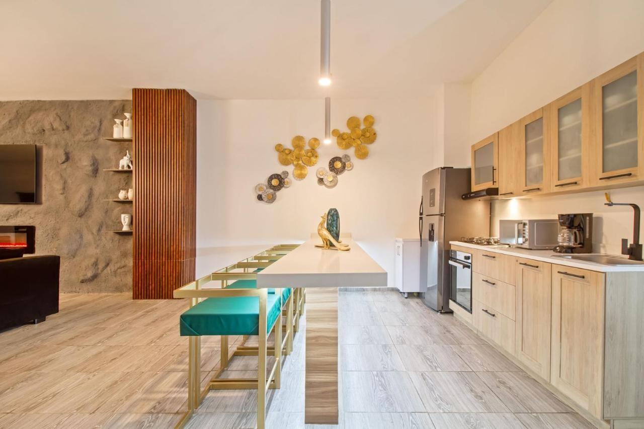 Cocina moderna con isla y taburetes verdes en apartamento de lujo cerca a Parque Lleras Medellín