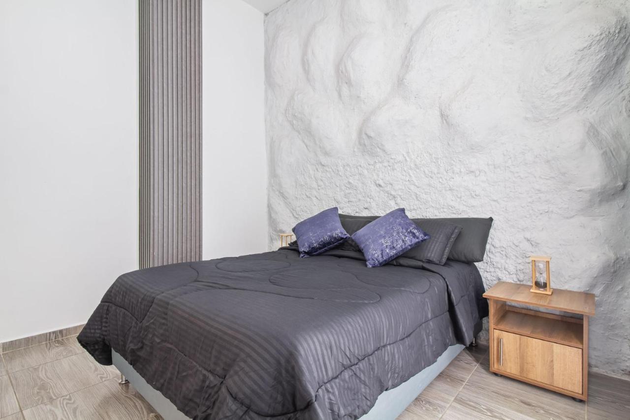 Habitación moderna con cama doble y pared de mármol en apartamento de Medellín cerca de Lleras