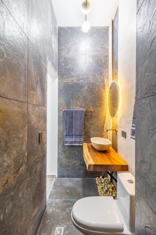 Baño moderno con acabados en mármol y madera en apartamento de lujo cerca de Lleras en Medellín