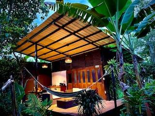 Terraza iluminada de loft en Armenia con hamaca y vegetación tropical nocturna