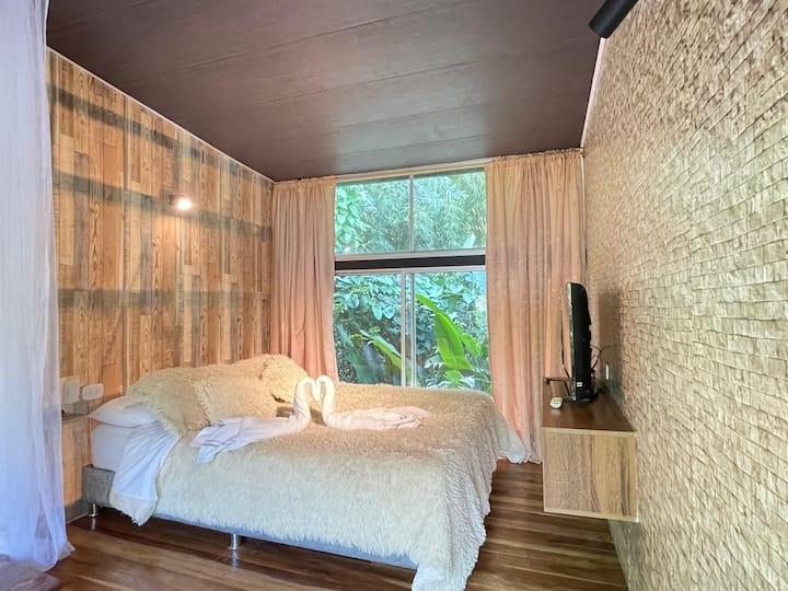 Habitación principal moderna con cama doble y ventanas grandes en loft Suite 505 Estocolmo Armenia