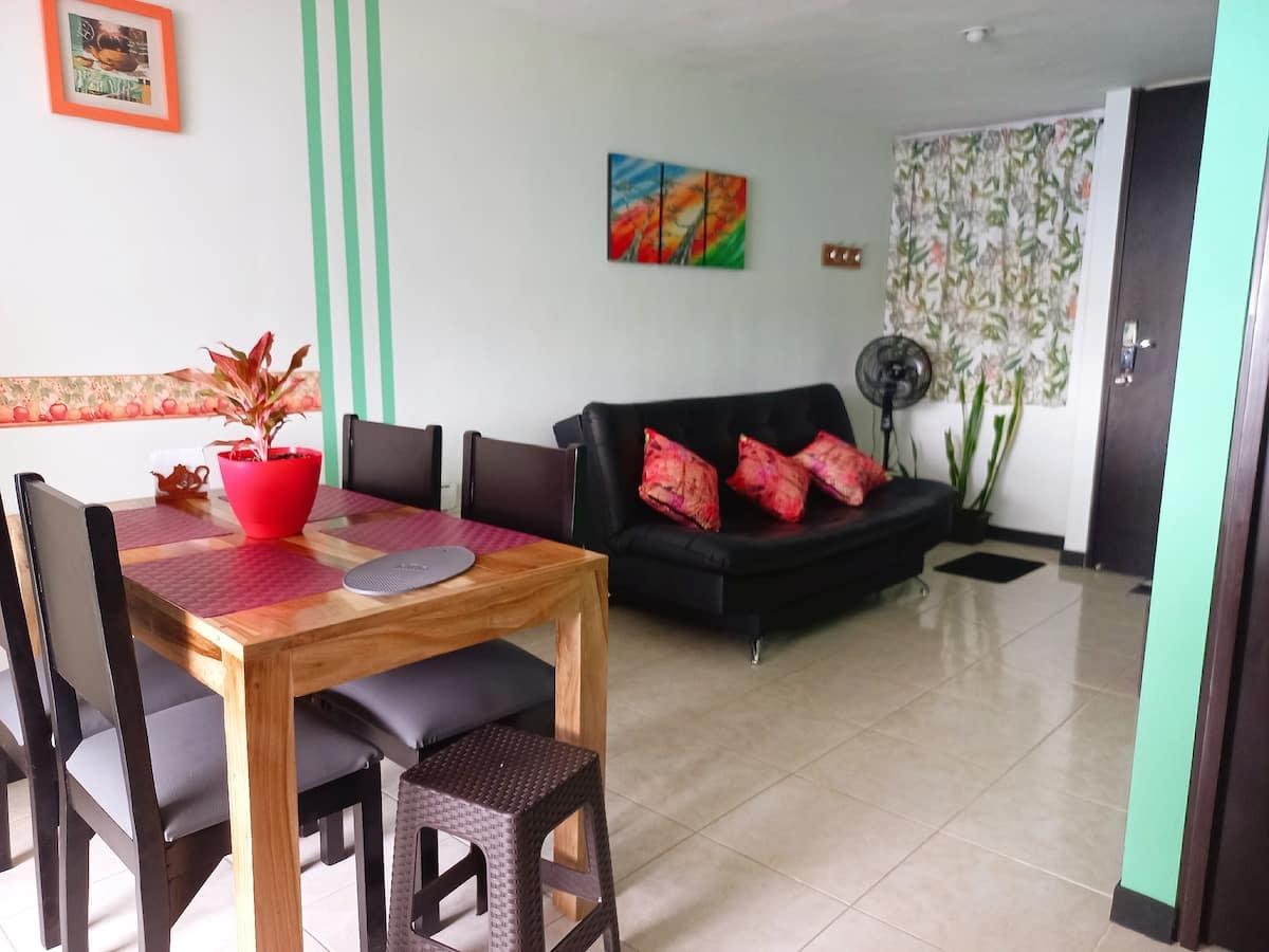 Sala comedor moderna con sofá negro y mesa de madera en ApartHotel Nathalie Montenegro