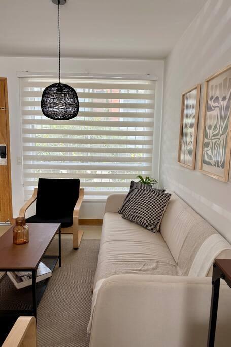 Sala de estar moderna en casa vacacional en Rionegro con sofá blanco, decoración minimalista y ventana amplia