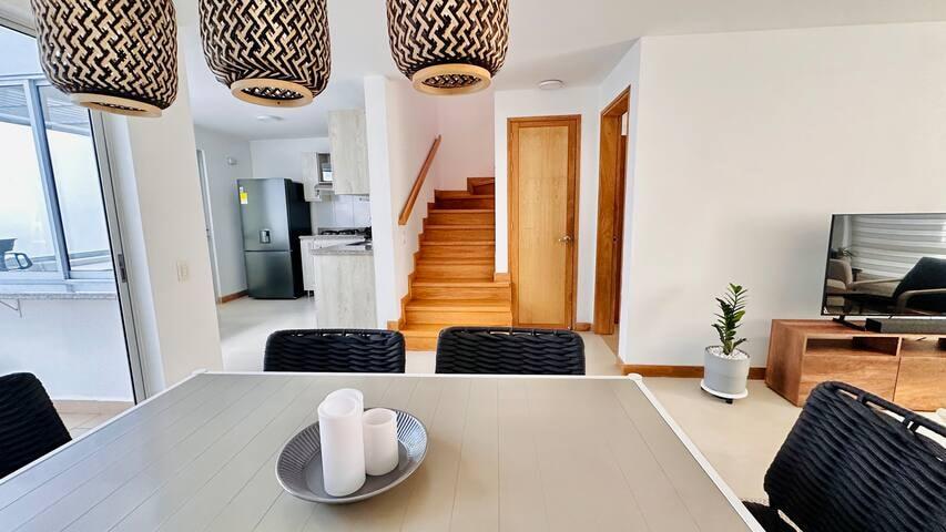 Comedor moderno con sillas negras y cocina al fondo en casa vacacional en Rionegro