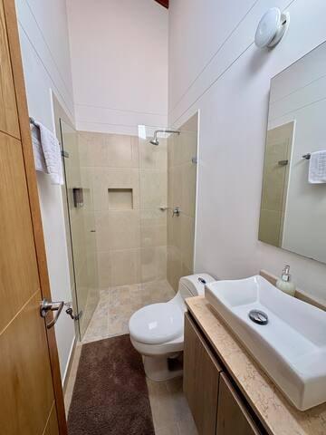 Baño moderno con ducha de vidrio, sanitario blanco y lavamanos vessel en casa de Rionegro