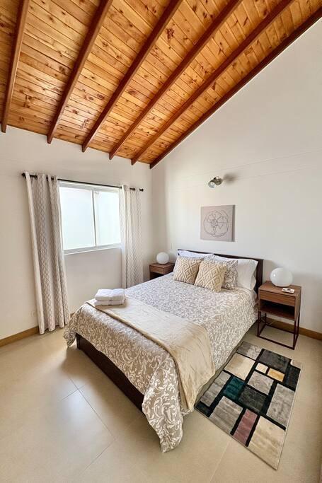 Habitación principal con cama doble, techo de madera y alfombra colorida en casa vacacional en Rionegro