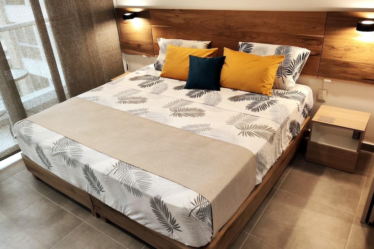 Habitación principal con cama king y cabecero de madera en apartamento moderno de Santa Marta
