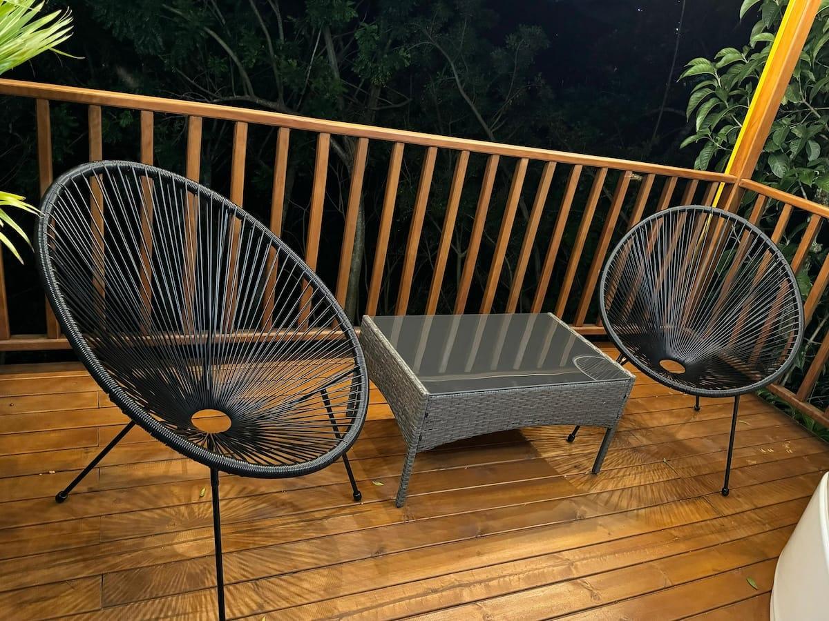 Terraza moderna con sillas Acapulco y mesa en cabaña de Girardota con vista al bosque