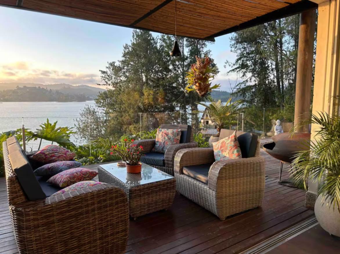 Terraza cubierta con muebles de mimbre y vista panorámica al lago en villa de lujo Guatapé