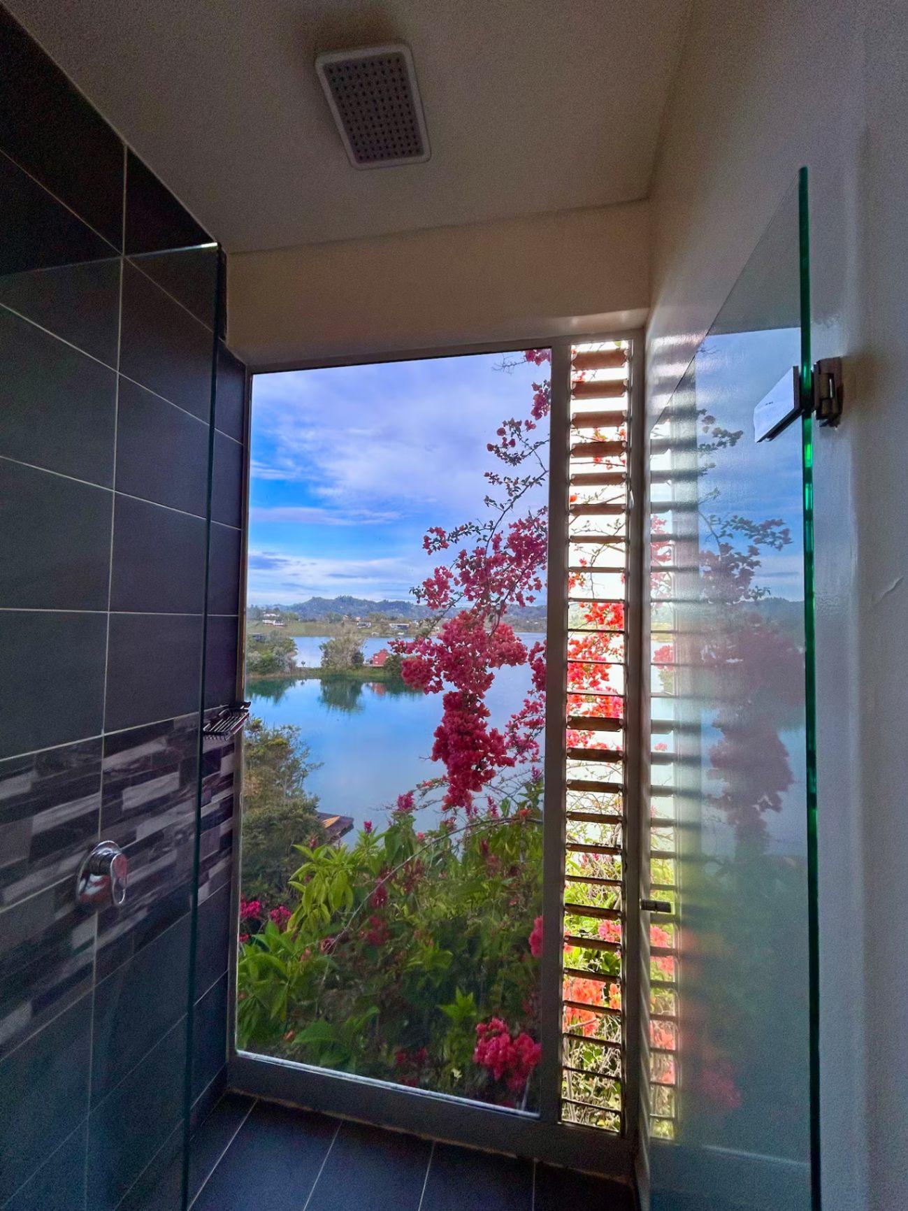 Baño moderno con ventana panorámica al lago de Guatapé en villa de lujo en Peñol