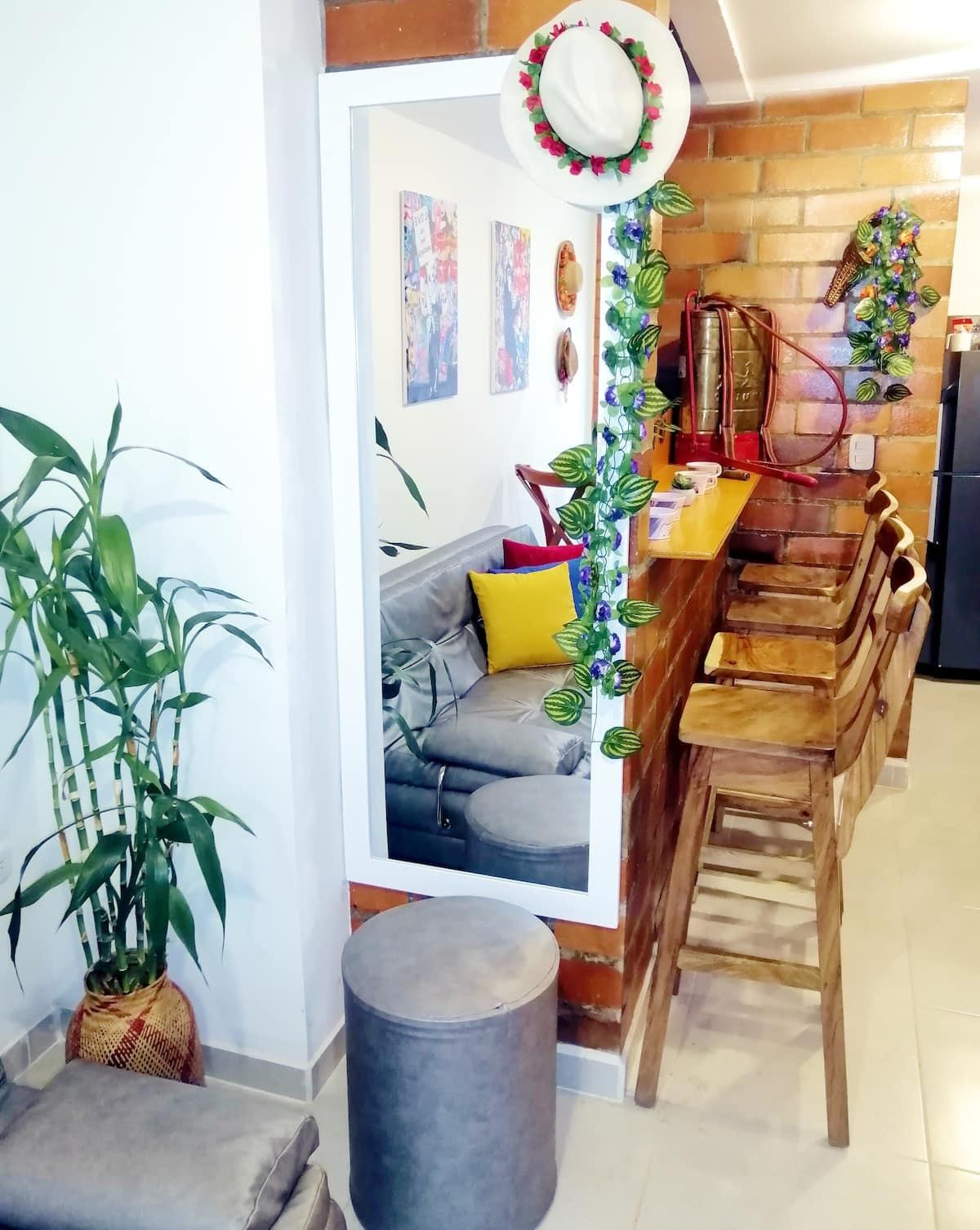 Zona social moderna con sillas de madera apiladas y decoración tropical en casa Montenegro Quindío
