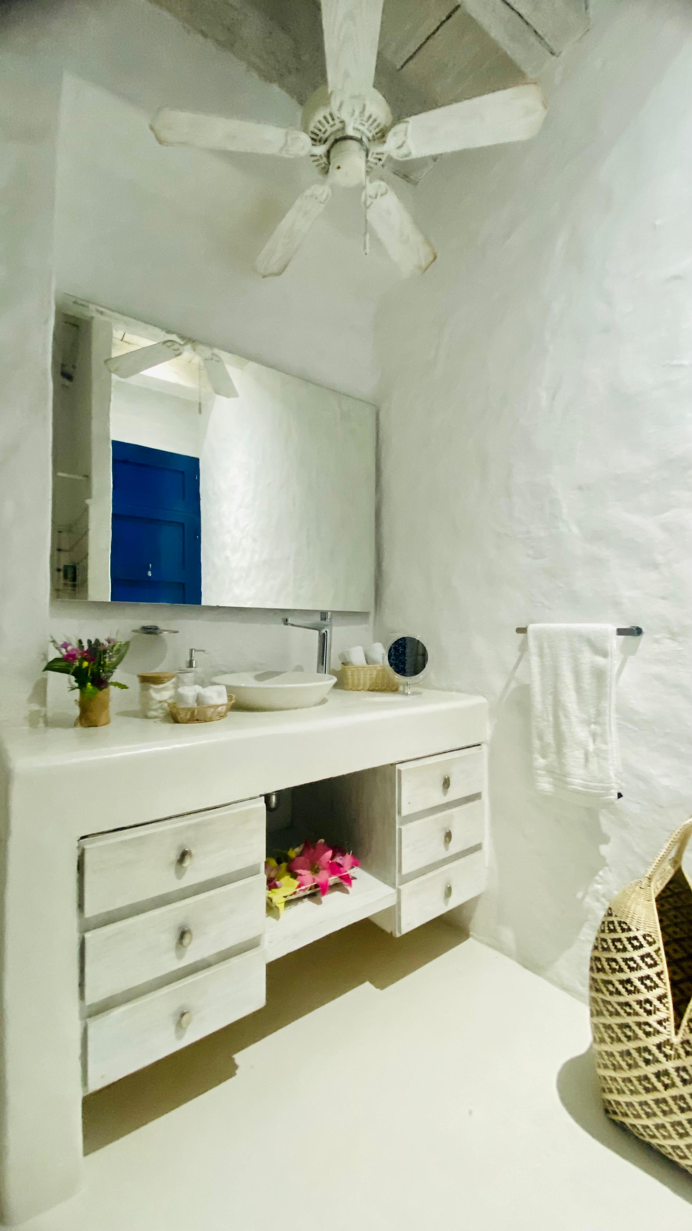 Baño elegante con vanidad blanca y espejo en casa privada de Cartagena de Indias