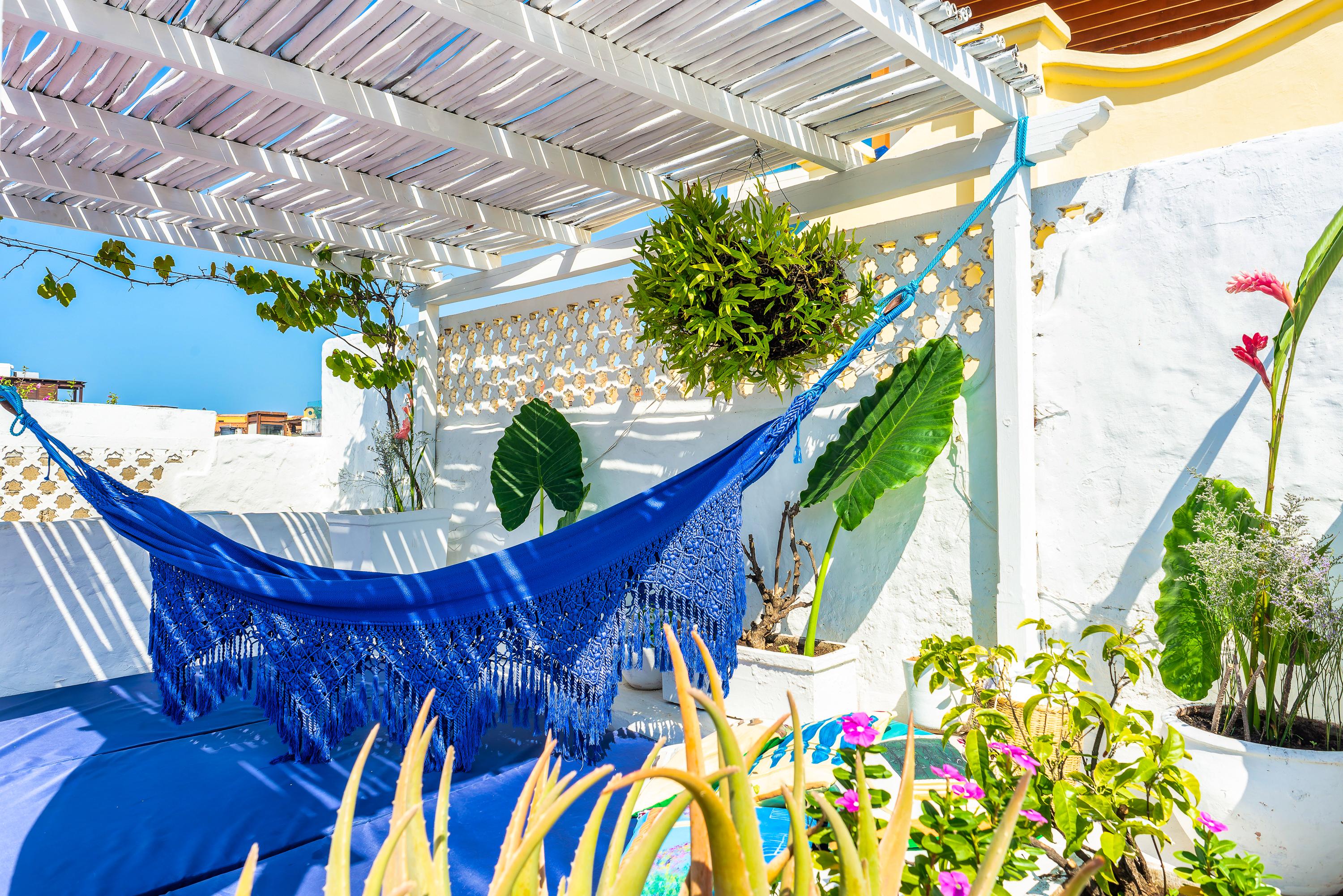 Terraza privada con hamaca azul, plantas tropicales y pergola blanca en casa de Cartagena de Indias