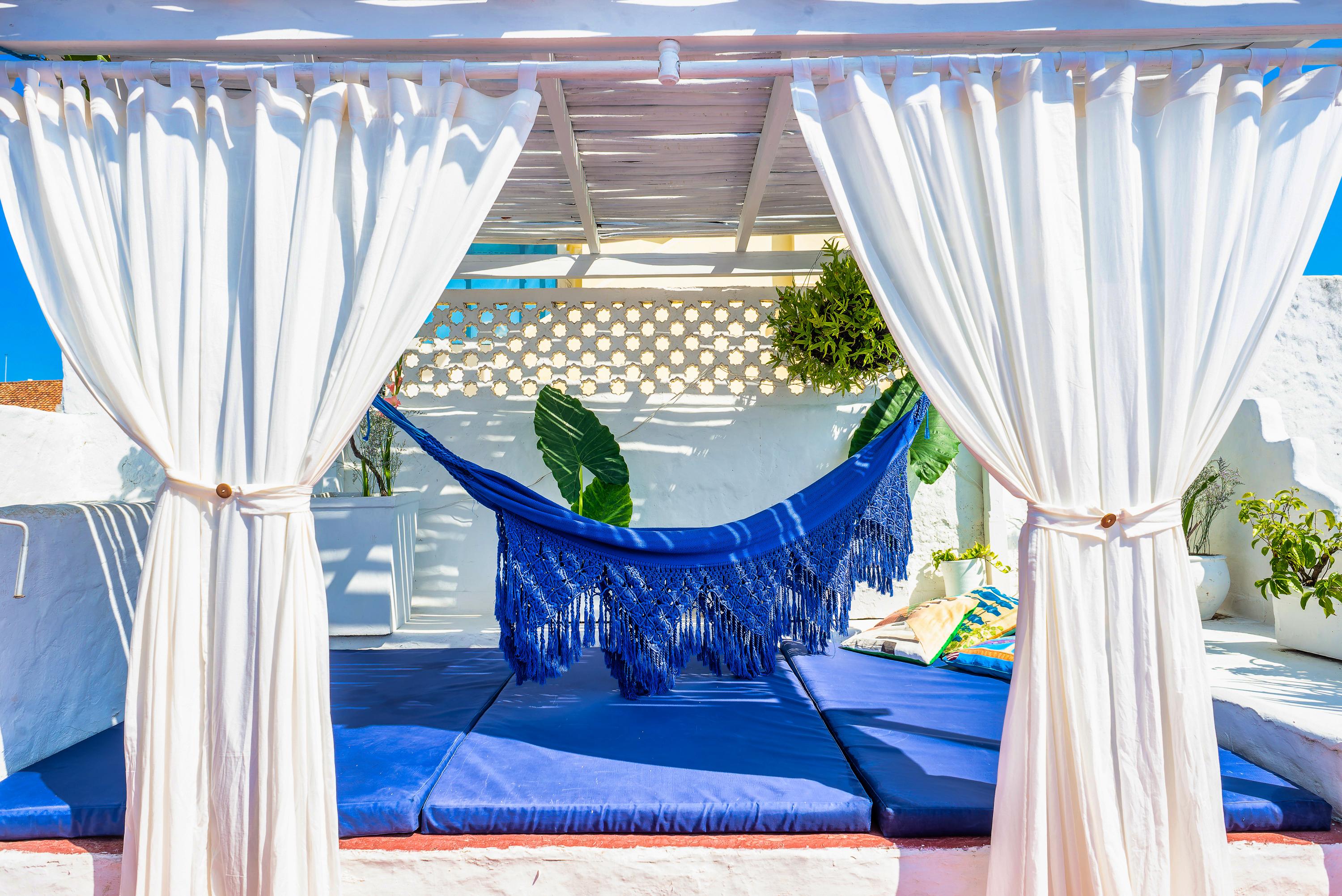 Terraza privada con hamaca azul y cortinas blancas en casa de Cartagena de Indias