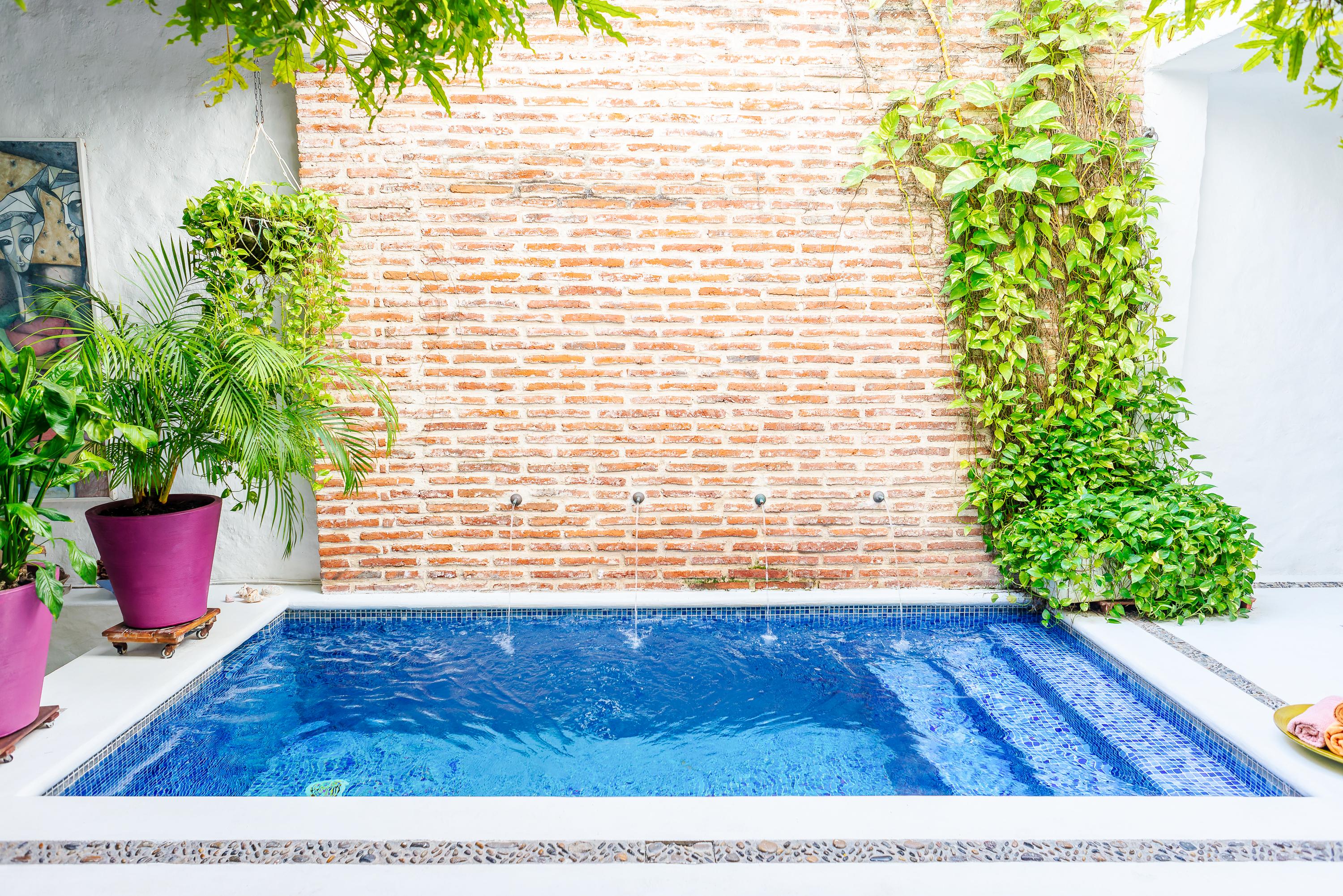 Piscina privada con jacuzzi y muro de ladrillo en casa vacacional de Cartagena de Indias
