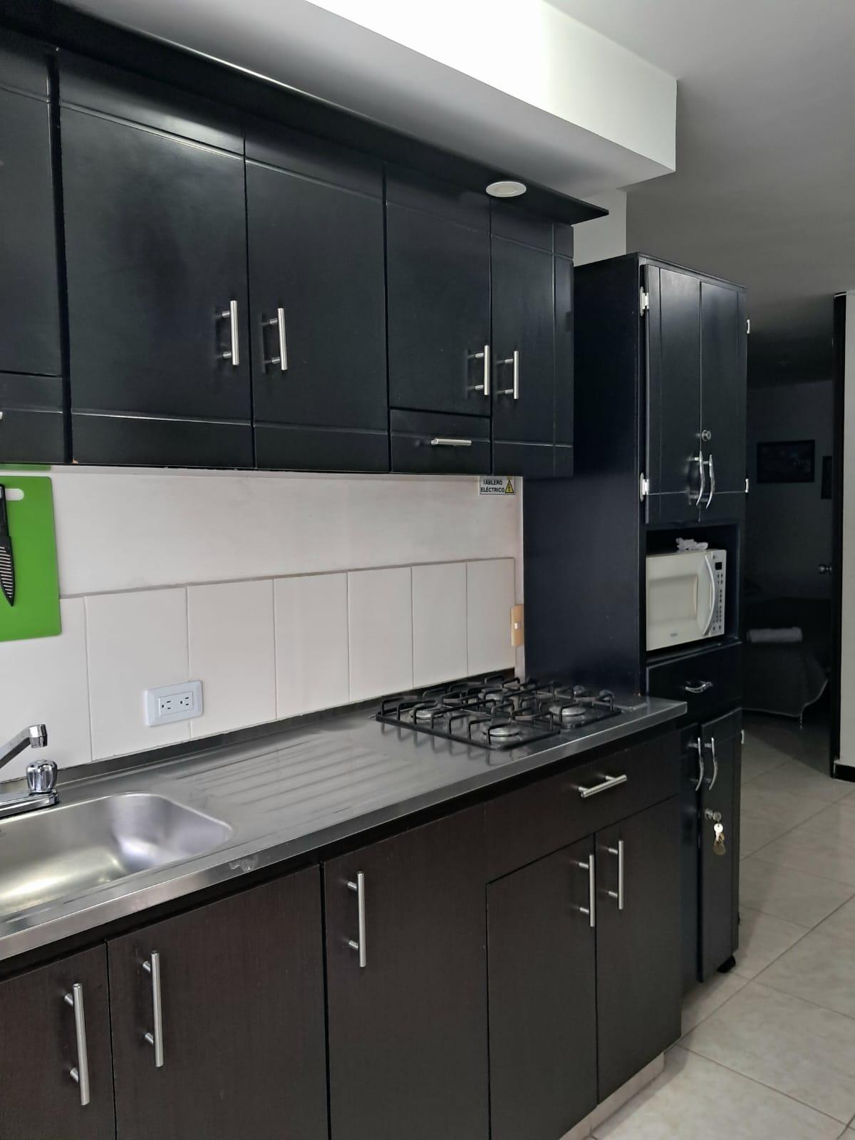 Cocina moderna con gabinetes negros y electrodomésticos en apartamento Montenegro cerca Parque del Café