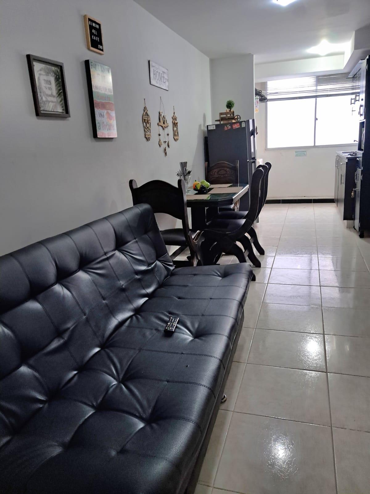 Sala de estar con sofa negro y comedor en apartamento Rincon del Cafe Montenegro