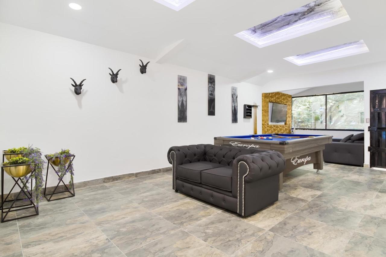 Elegante sala de juegos con mesa de billar y sofá Chesterfield en apartamento de lujo en Medellín