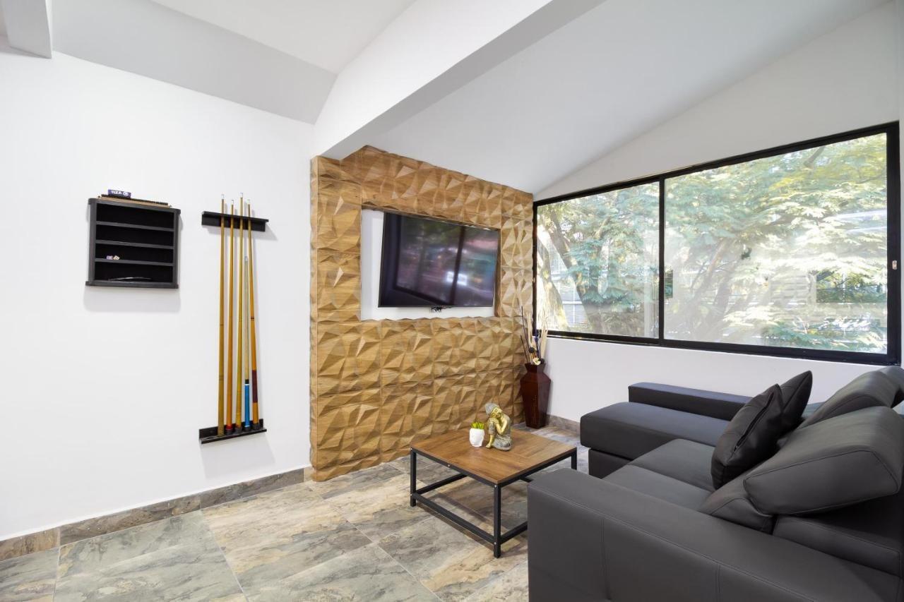 Sala moderna con sofá gris y TV en apartamento de lujo en Provenza Medellín