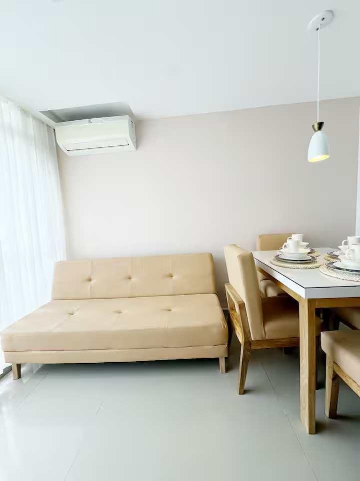 Sala comedor moderna con sofá beige y mesa de madera en apartamento Cartagena de Indias