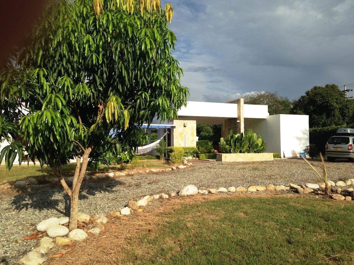 Casa tropical con amplio jardín y parqueadero en Apulo, rodeada de vegetación exuberante y árboles frutales