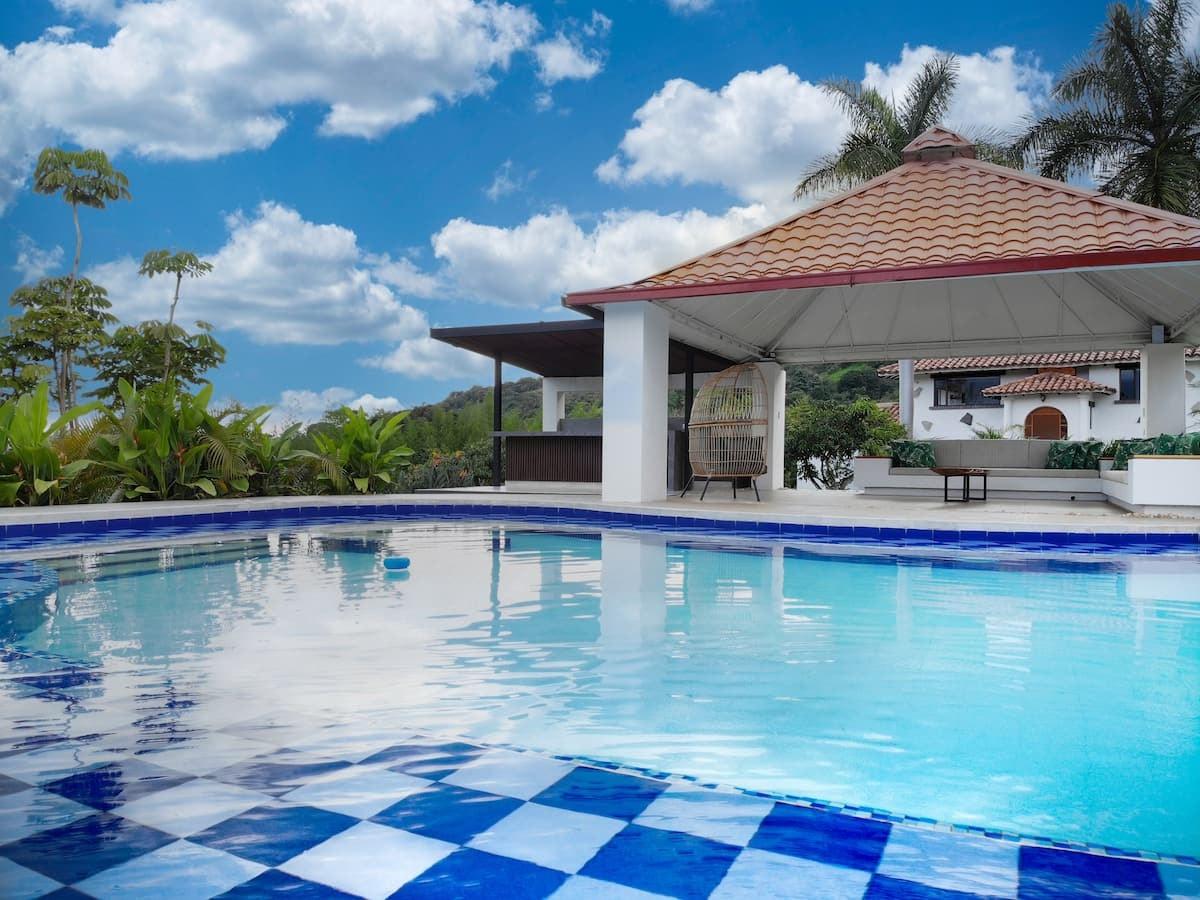Piscina con azulejos azules y blancos en casa vacacional tropical en Apulo con palmeras