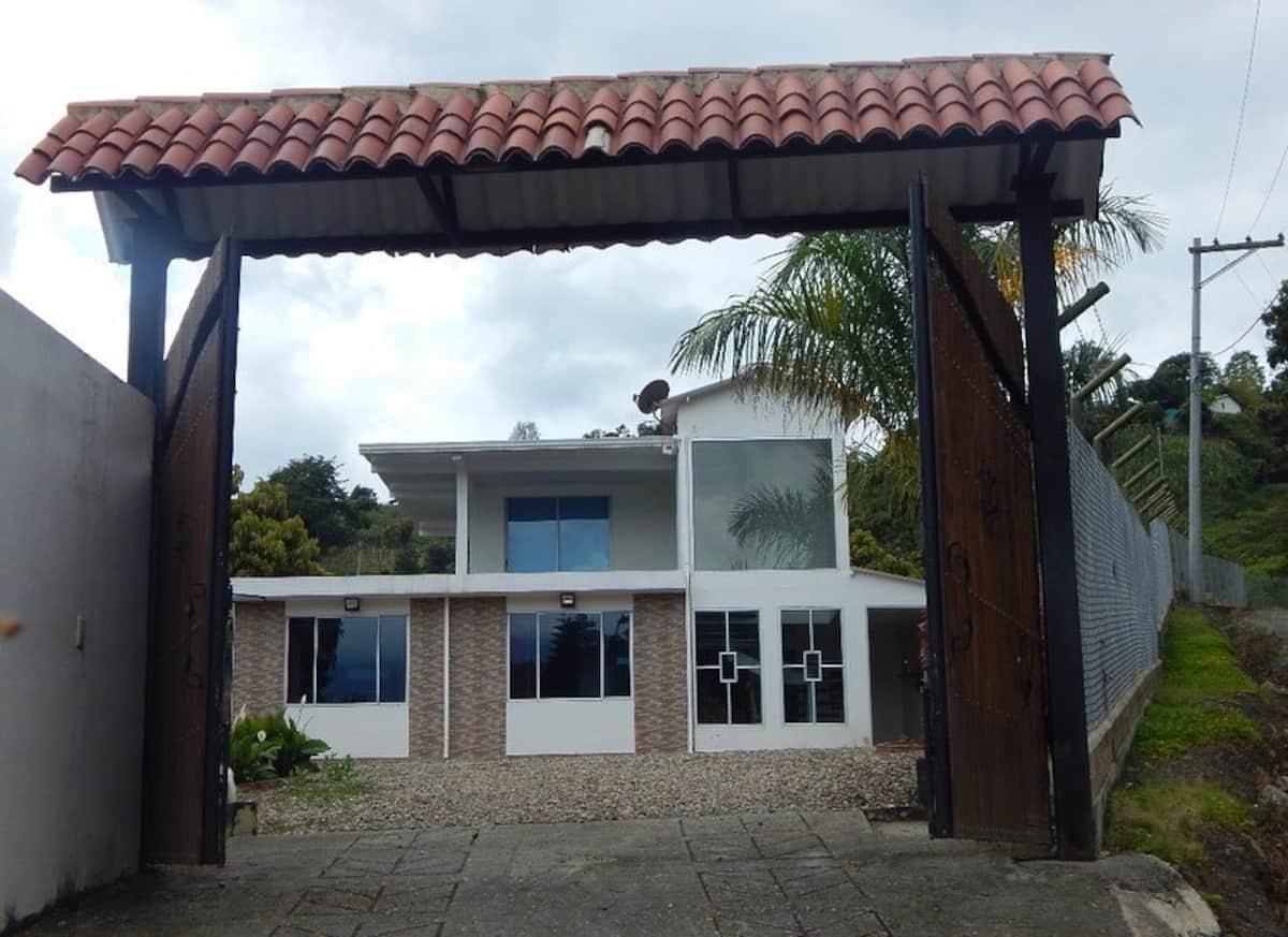Fachada principal de casa vacacional tropical con entrada cubierta y diseño moderno en Apulo