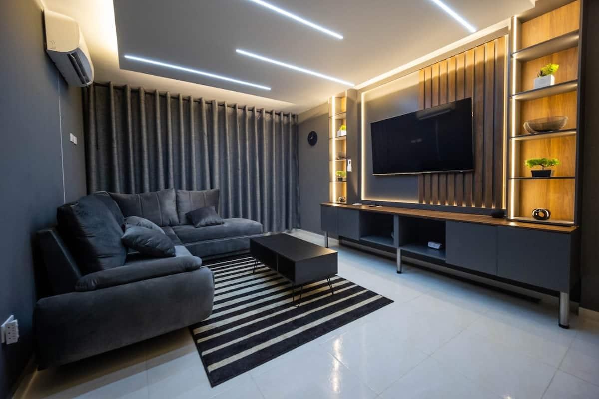 Sala moderna con sofá gris, TV y iluminación LED en apartamento inteligente en Cúcuta