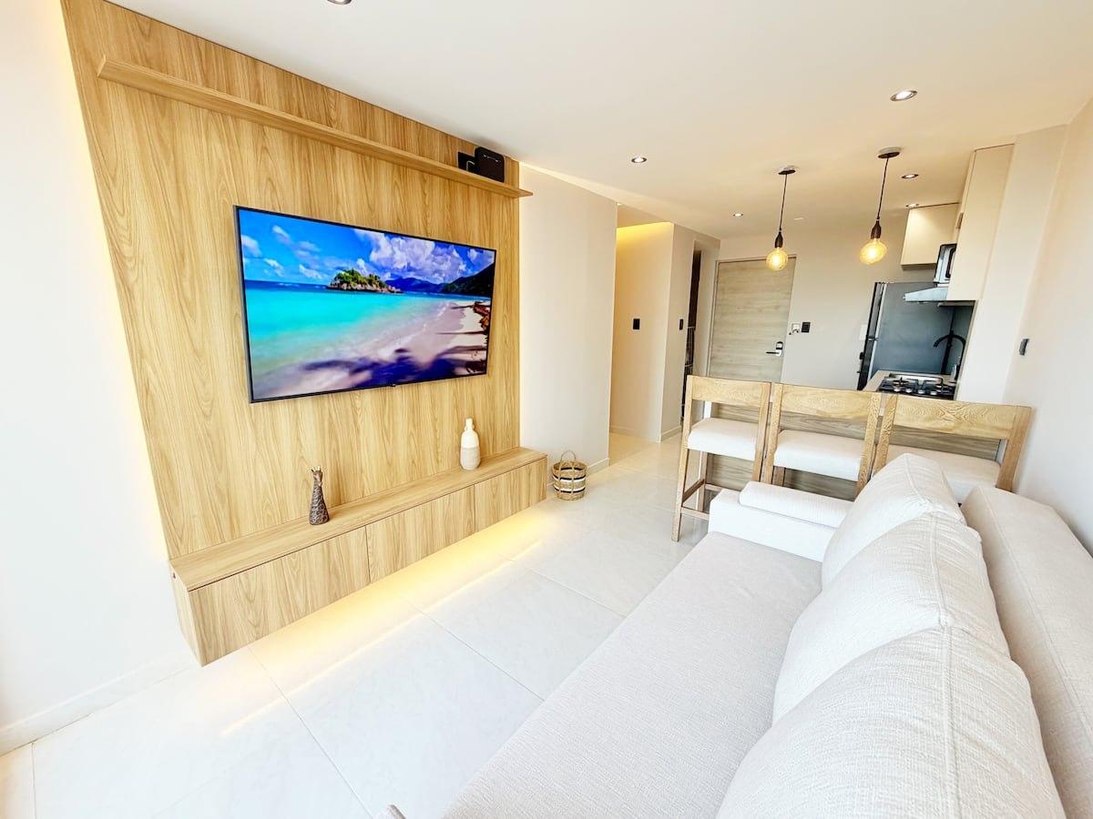 Sala moderna de apartamento con TV gran pantalla y cocina integrada en Cartagena