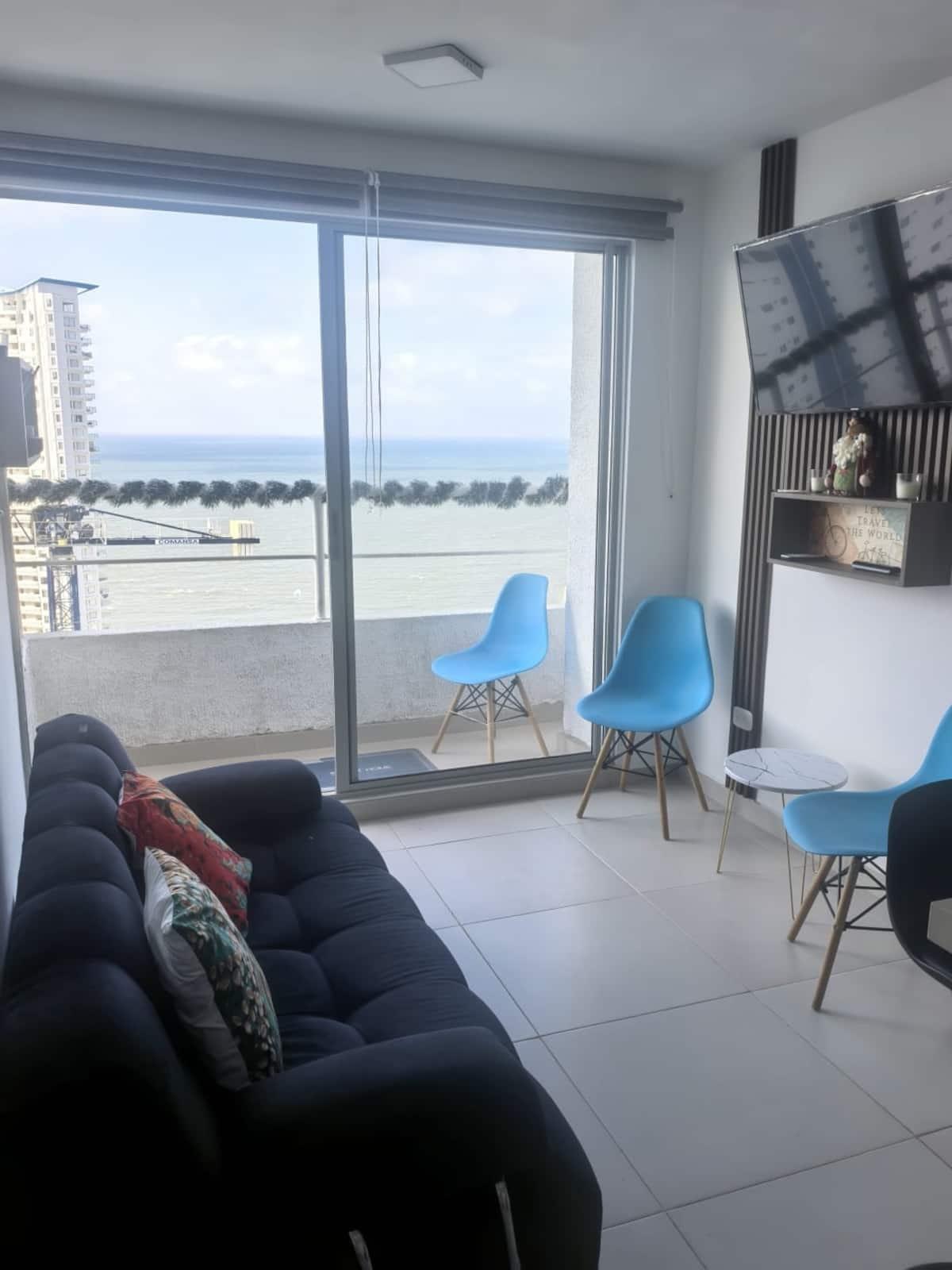 Sala de estar moderna con vista al mar y muebles azules en apartamento de Cartagena