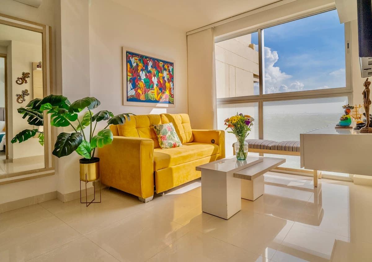 Sala moderna con sofá amarillo y vista al mar en apartamento céntrico de Cartagena