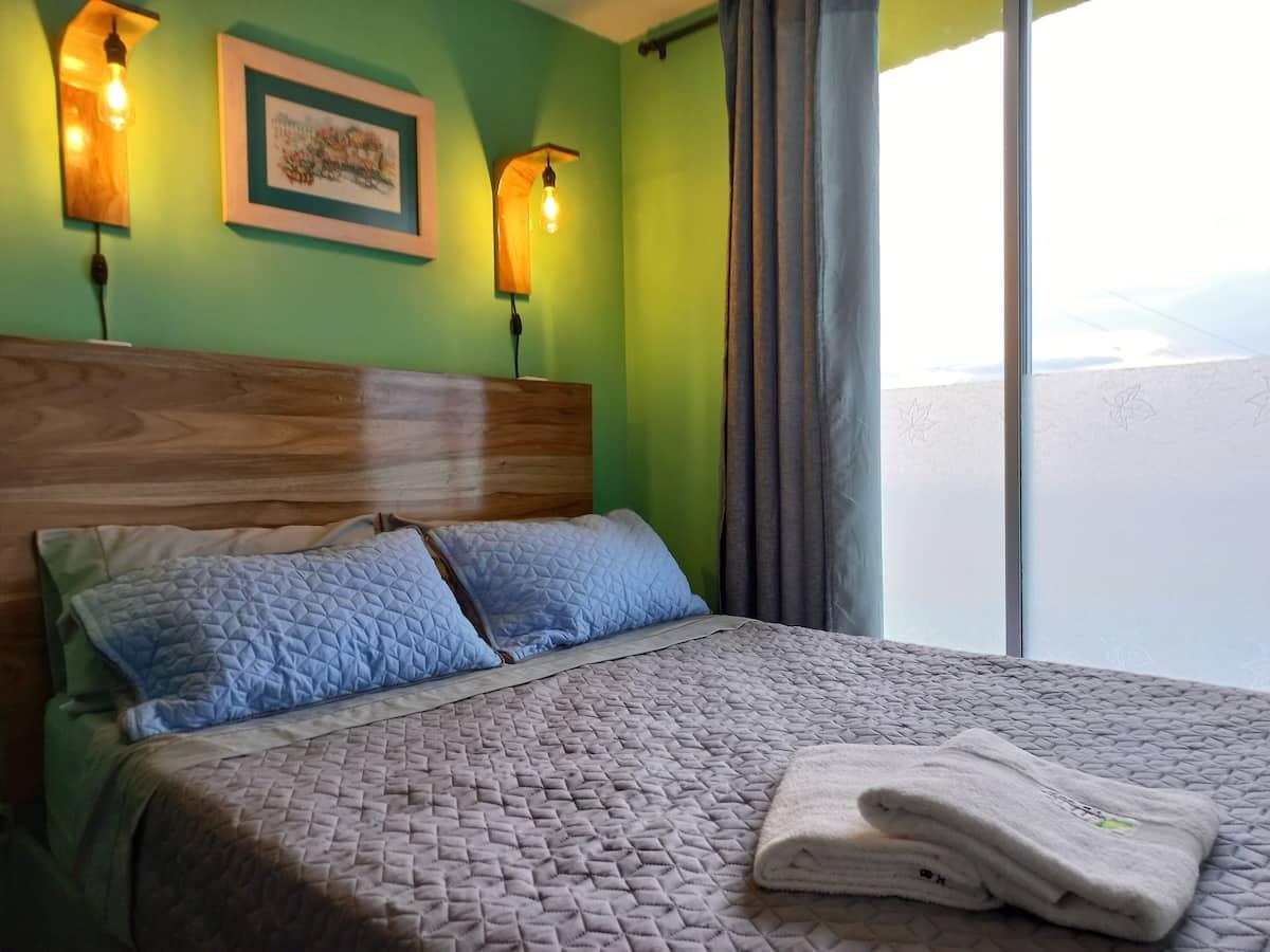 Habitación moderna con cama doble y decoración verde en ApartHotel Nathalie Montenegro