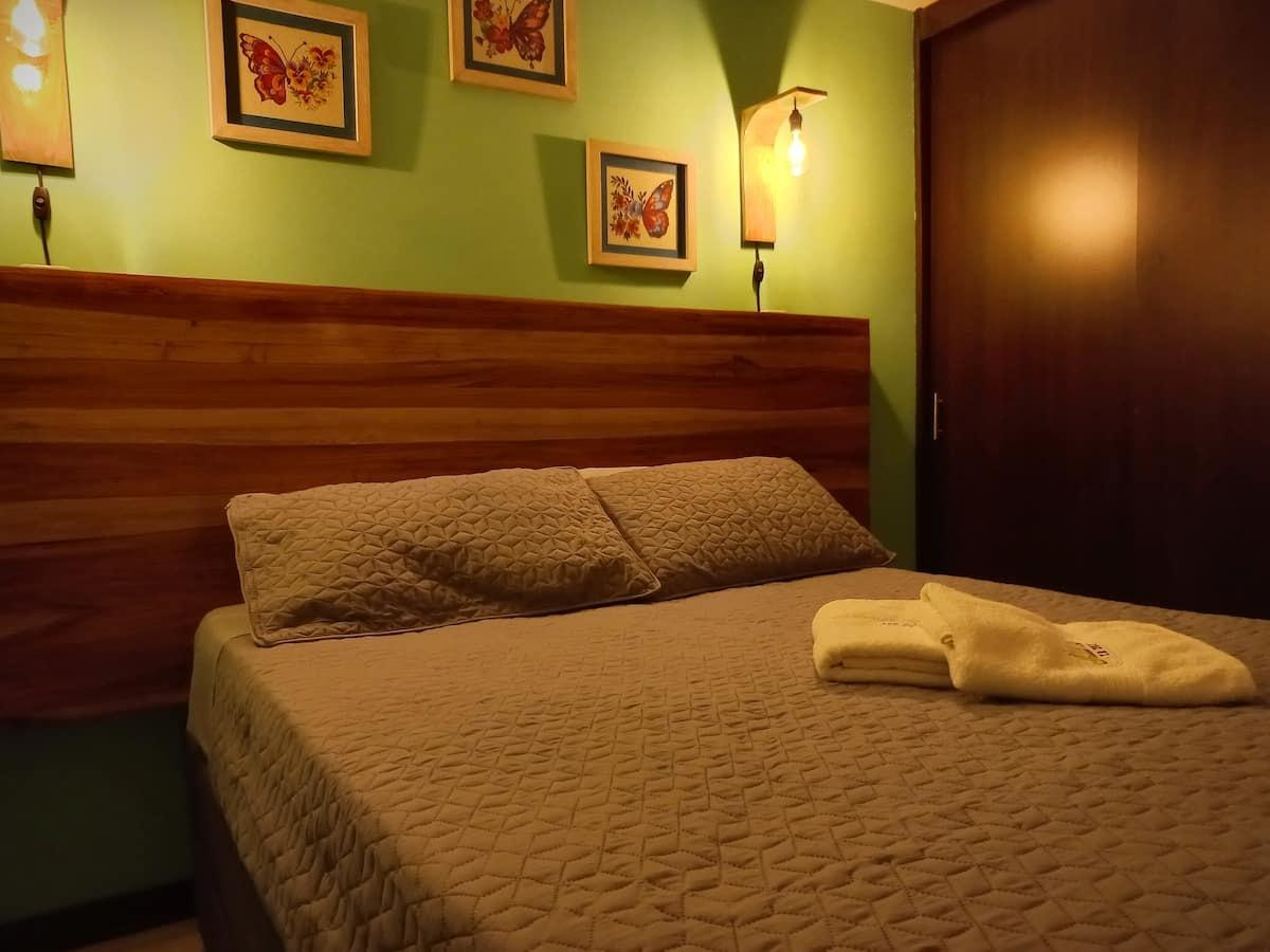 Habitación con cama doble y decoración de mariposas en ApartHotel Nathalie Montenegro cerca Parque del Café