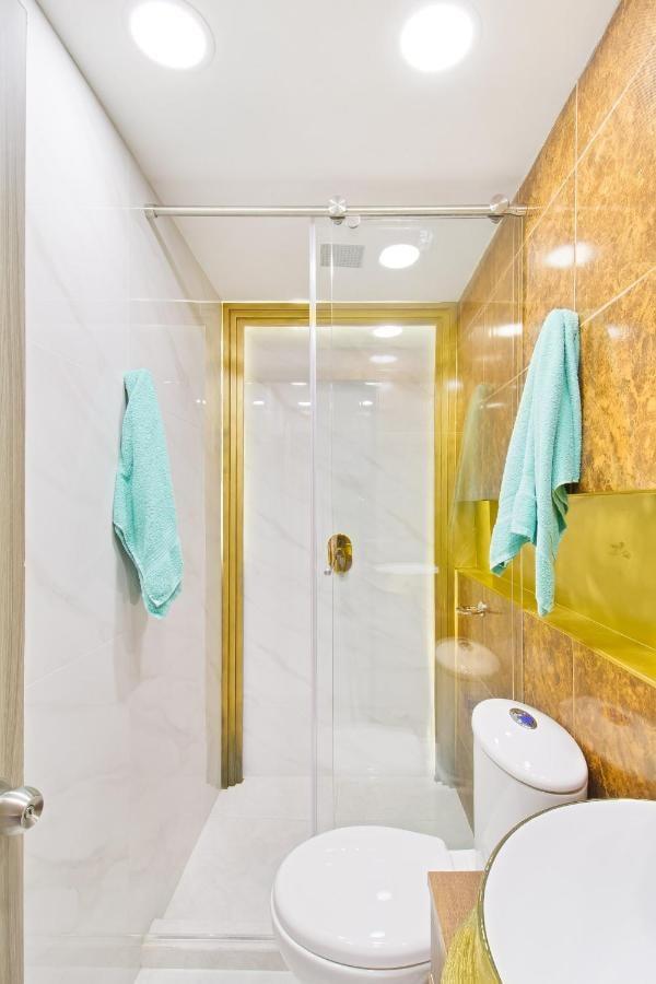 Baño moderno con ducha de vidrio y acabados dorados en apartamento de Medellín cerca al Parque Lleras