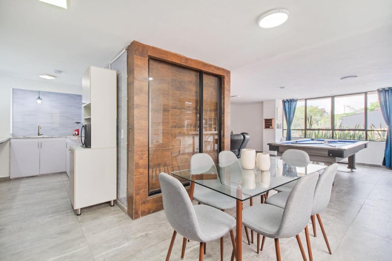 Comedor moderno con mesa de vidrio y sillas grises en apartamento de Medellín cerca del Parque Lleras