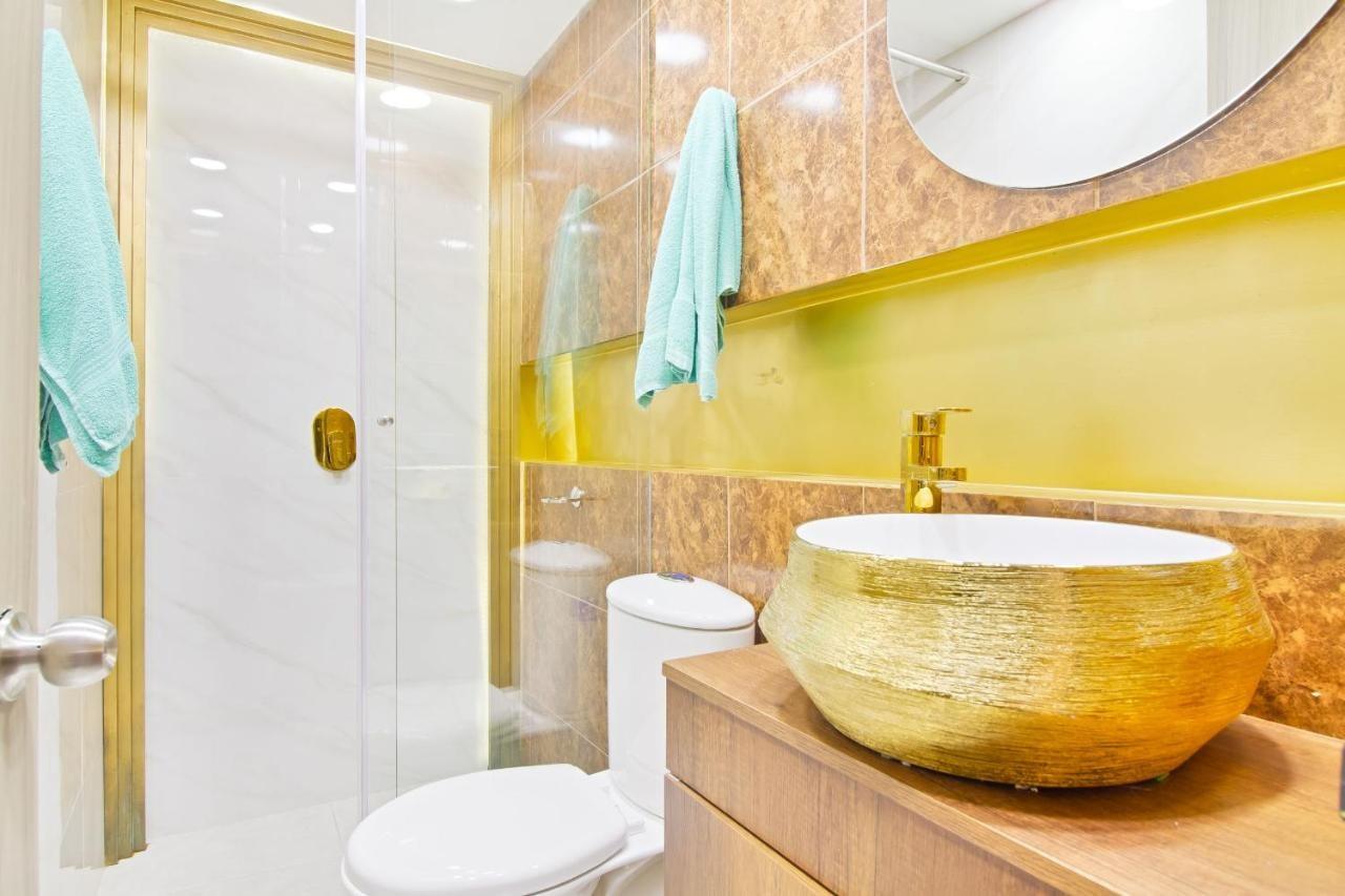 Baño moderno con lavamanos dorado y acabados de lujo en apartamento cerca Parque Lleras Medellín
