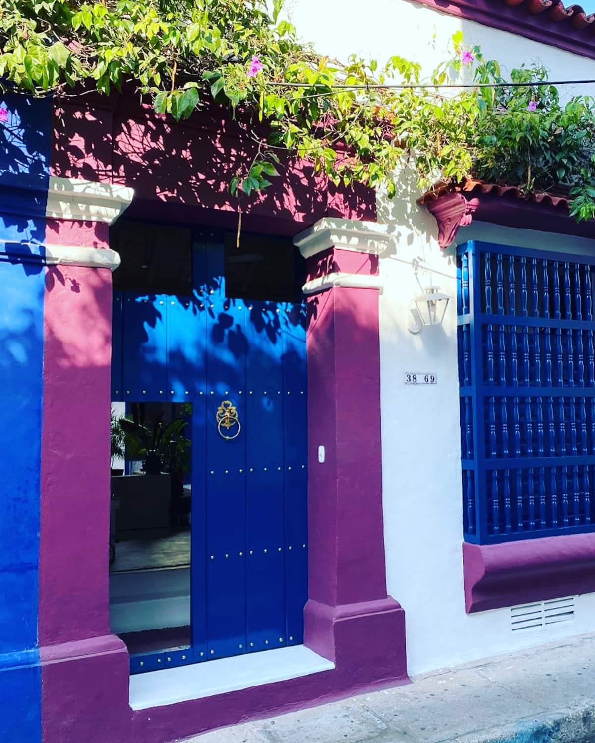 Entrada principal de casa colonial privada en Cartagena con puerta azul y columnas rosadas
