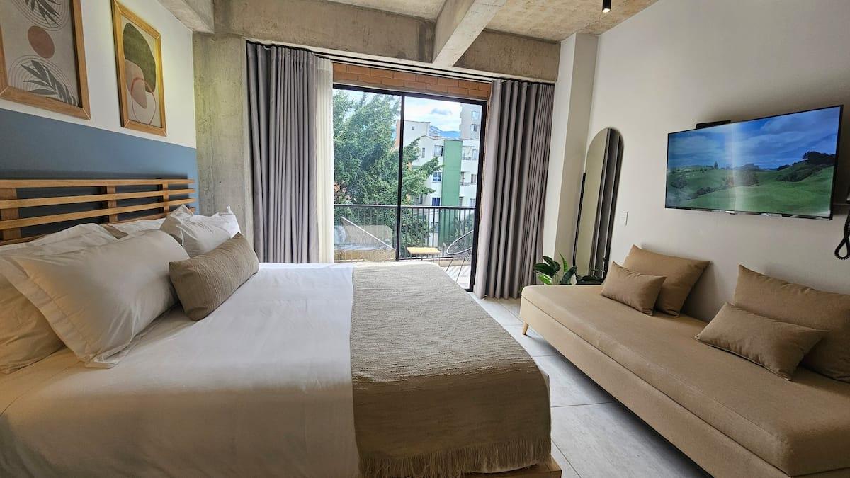 Habitación principal de loft moderno en Medellín con balcón, aire acondicionado y televisor