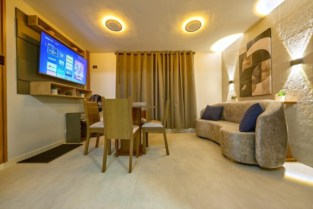 Sala comedor moderna con sofá gris, mesa de madera y TV en apartamento Mi segunda morada Cúcuta