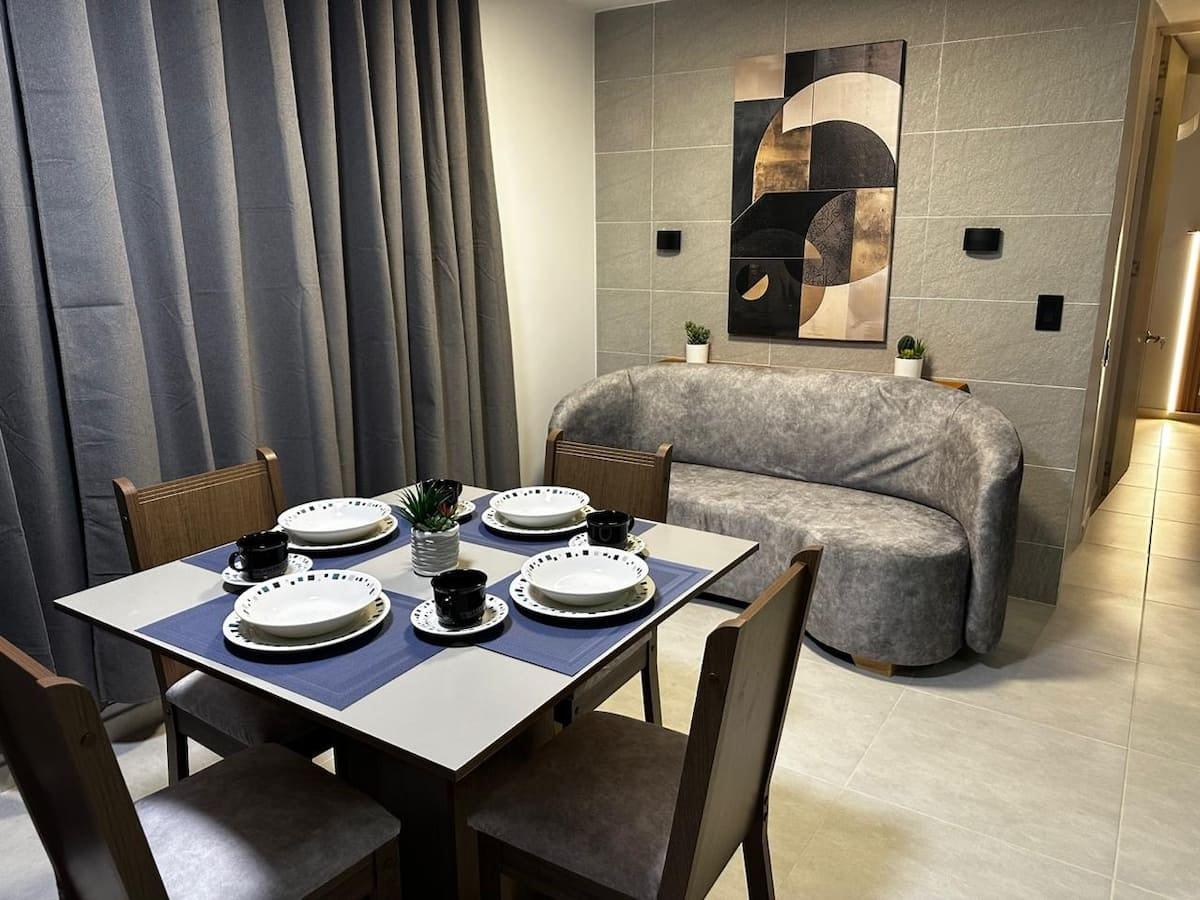 Comedor elegante con mesa servida y sofá gris en apartamento Mi segunda morada Cúcuta