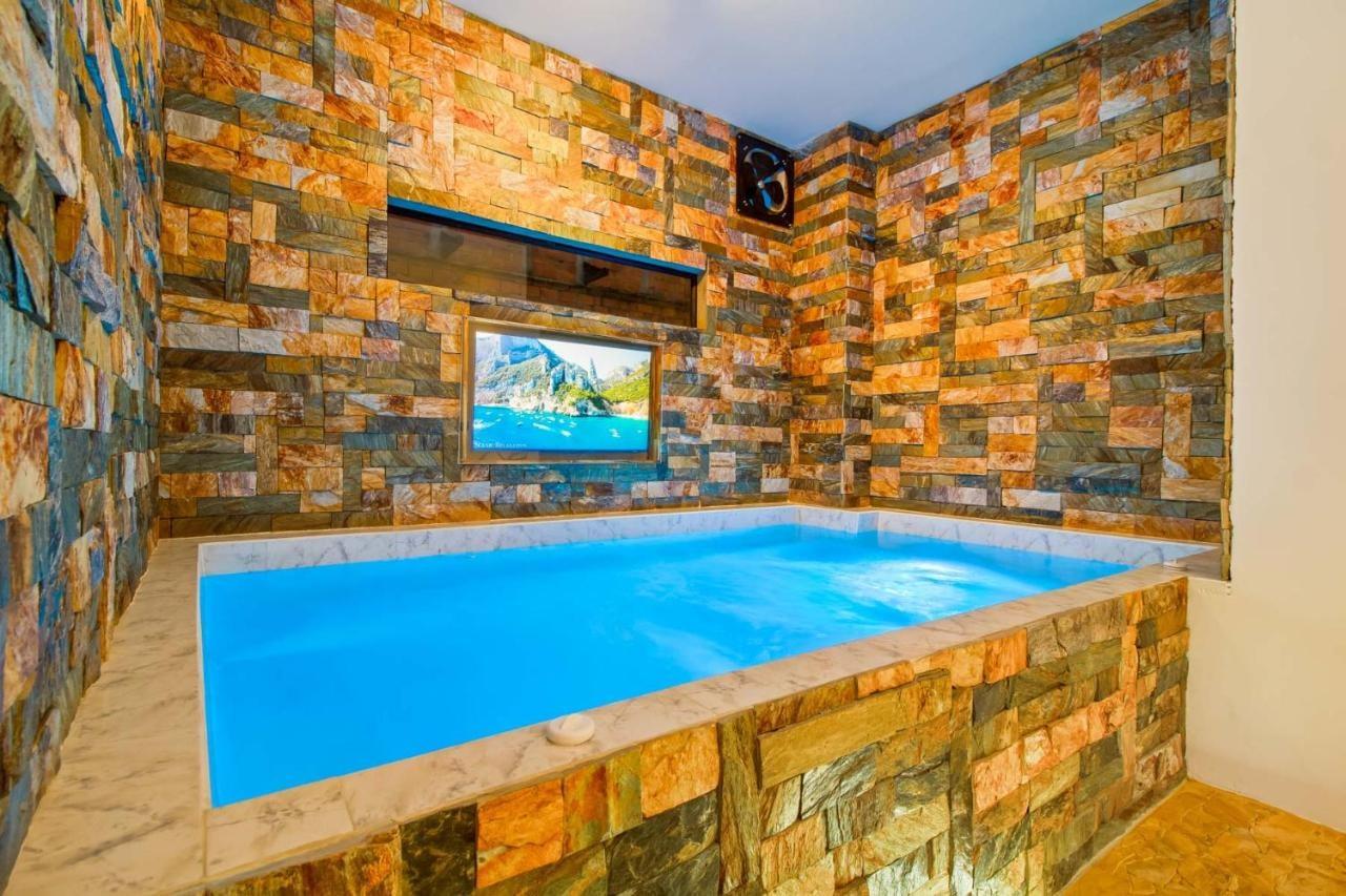 Jacuzzi privado con paredes de piedra natural y televisión en apartamento de lujo cerca de Lleras en Medellín